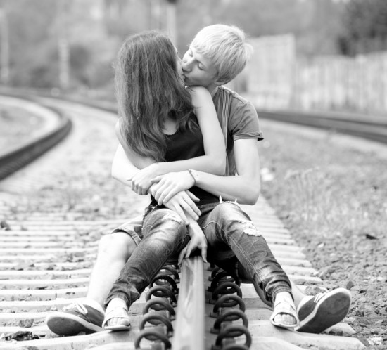 Couple kissing at railway. Photo in black and white style.